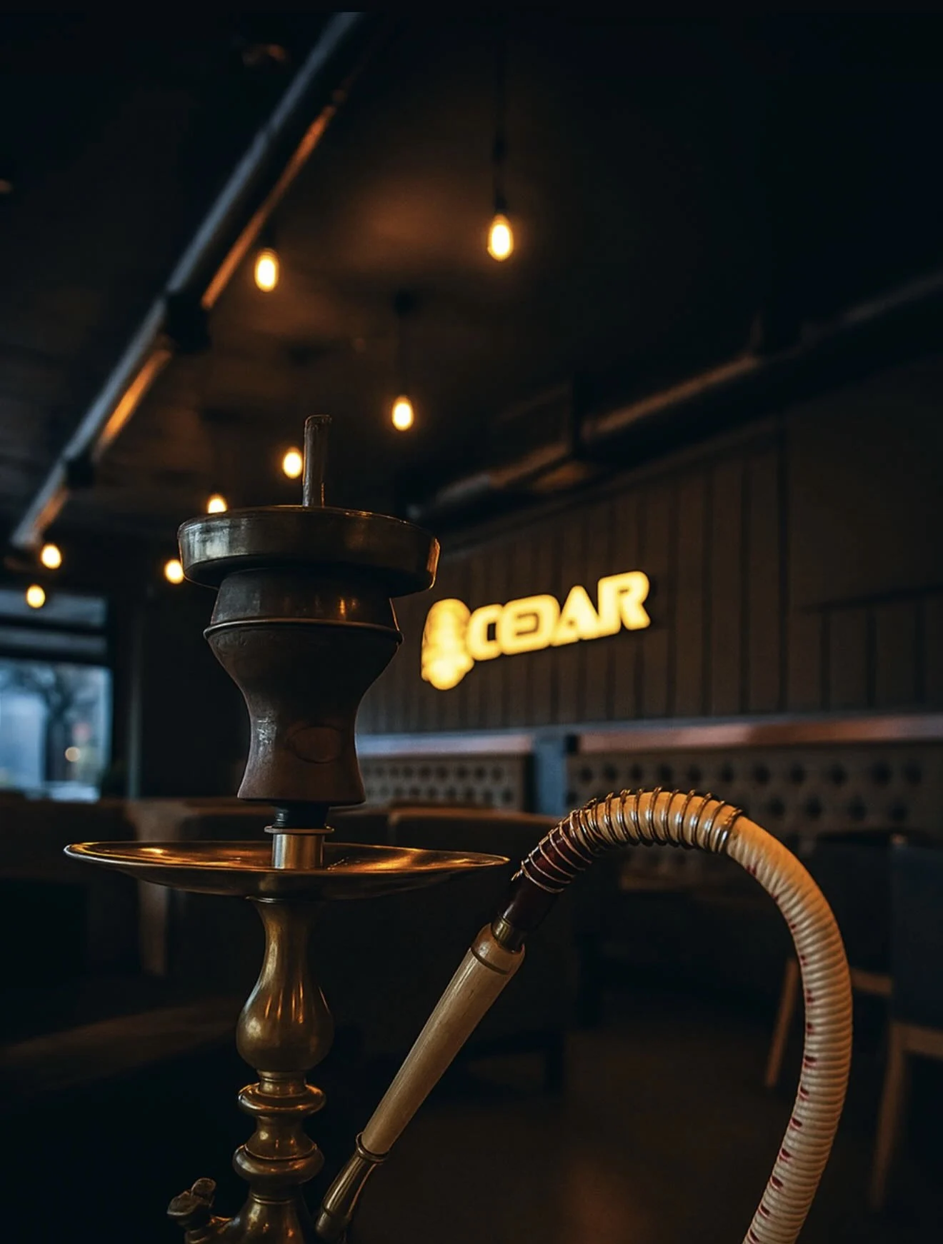 A traditional brass shisha in the Cedar lounge, CEDAR sign glowing behind